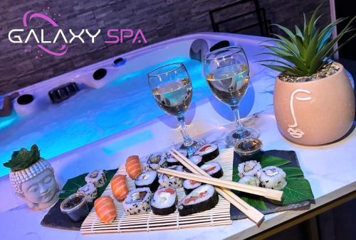 une table avec des sushis et deux verres de vin dans l'établissement GALAXY SPA - Suite Mercure Jacuzzi Privatif, à Champigneulles