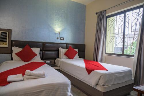 2 camas en una habitación de hotel con almohadas rojas en Pallavi International, en Calcuta