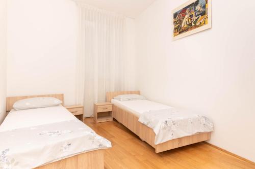 two beds in a room with white walls and wooden floors at Apartment Hani Koper in Koper