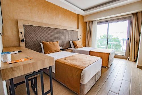 a hotel room with two beds and a desk at point beach hotel in Marmaris