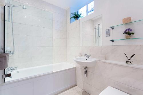 a white bathroom with a tub and a sink and a bath tubermott at Veeve - Village Beauty in London