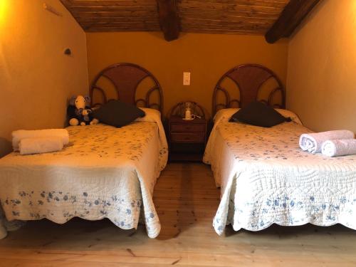 a bedroom with two beds with a teddy bear sitting between them at Casa Mediodía in Villanueva de los Caballeros