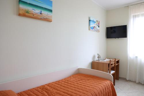 a bedroom with a bed with an orange blanket and a television at Tenuta Albachiara in Naso