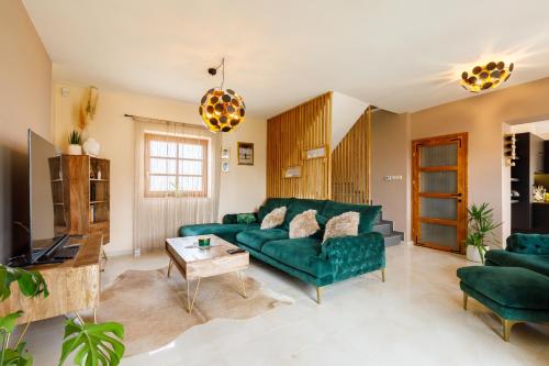 a living room with a green couch and a table at KUMBHAKA Villa in Csopak