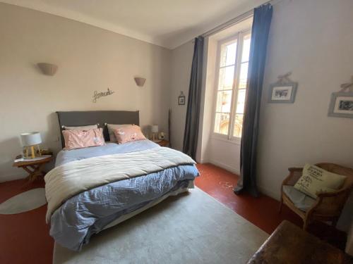 - une chambre avec un lit doté d'oreillers roses et d'une fenêtre dans l'établissement La Capucine, à Cavaillon