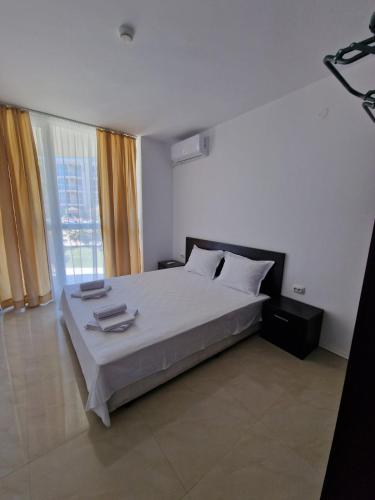 a bedroom with a large bed and a large window at Апартамент МеГи in Burgas
