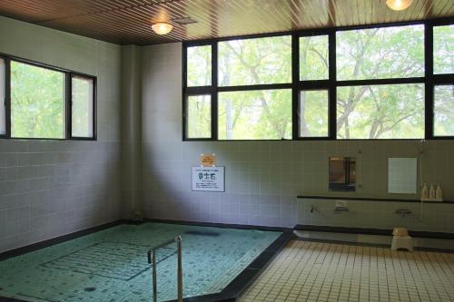 ein Bad mit einem Pool in einem Zimmer mit Fenstern in der Unterkunft Yatsugatake Grace Hotel in Minamimaki