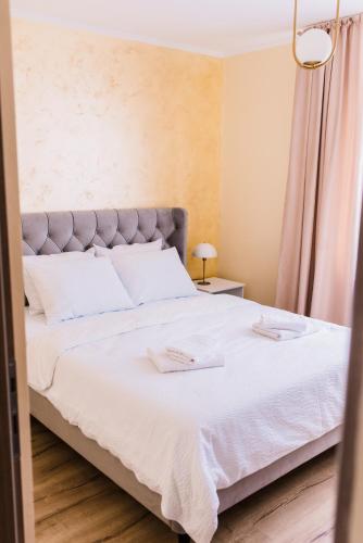 a bedroom with a large bed with white sheets at Central White Apartment in Satu Mare