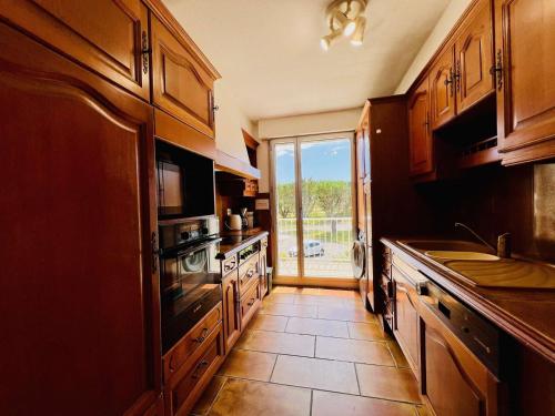 une cuisine avec des placards en bois et une grande fenêtre dans l'établissement Quiberon - Appartement 3 pièces avec Wifi, Parking et Animaux acceptés - FR-1-478-3, à Quiberon