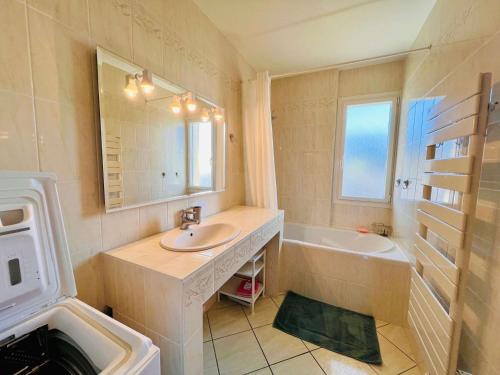 une salle de bain avec un lavabo, une baignoire et un miroir dans l'établissement Quiberon - appartement 3 pièces - 56m² - proche centre - garage - loggia - sans animaux - FR-1-478-99, à Quiberon