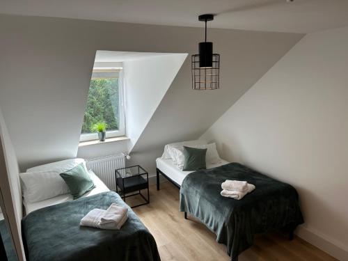 a attic room with two beds and a window at Moderne Wohnung in zentraler Lage, Schallschutzfenster, Self-check-in, Netflix, Disney Plus in Hannover