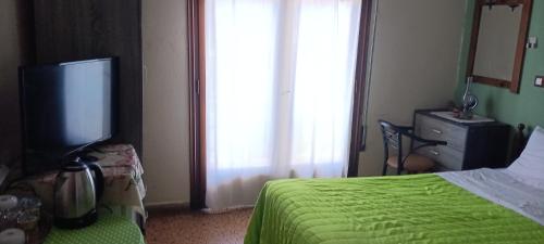 a bedroom with a bed and a flat screen tv at Hotel zakros rooms-restaurant in Zákros