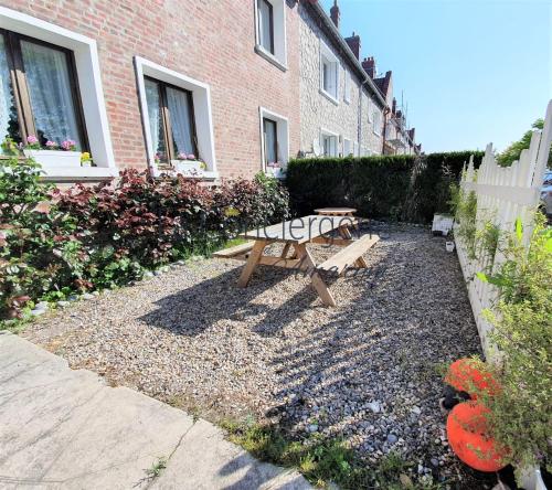 une table de pique-nique et un banc dans une cour à côté d'un bâtiment dans l'établissement Le Maluthina Maison Familiale au Hourdel entre Mer & Nature, à Cayeux-sur-Mer