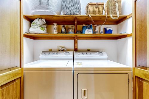 eine Waschmaschine und einen Trockner in einer Küche mit Holzregalen in der Unterkunft Cape Springs Cottage in Chatham