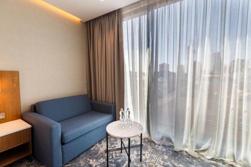 a room with a blue chair and a large window at Piazza Epigraph in Batumi