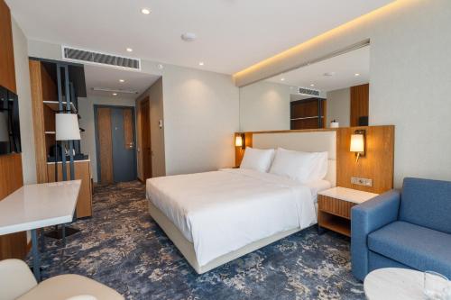a hotel room with a bed and a blue chair at Piazza Epigraph in Batumi