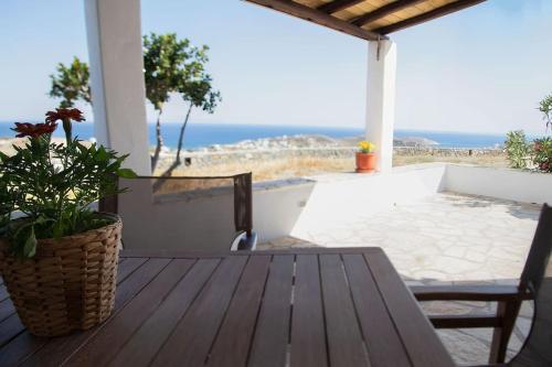 a porch with a wooden table and a view of the ocean at Amarados Studio Syros in Vari