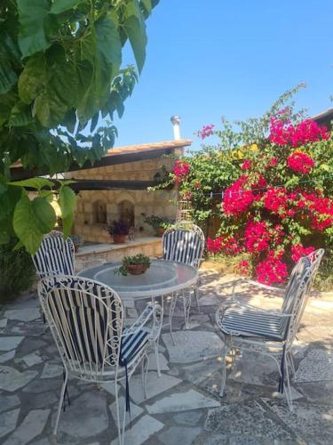 three chairs and a table in a yard with flowers at Ivi's House Giolou in Paphos City
