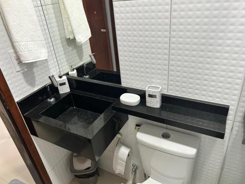 La salle de bains est pourvue de toilettes et d'un comptoir noir. dans l'établissement SEU LAR, à Campina Grande