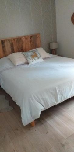 - un lit avec des draps et des oreillers blancs dans une chambre dans l'établissement gite l oree de la foret, à Incheville