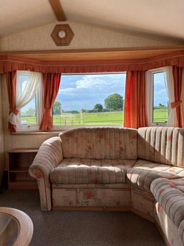 a living room with a couch and a large window at The Paddock View at Danebury in Stockbridge