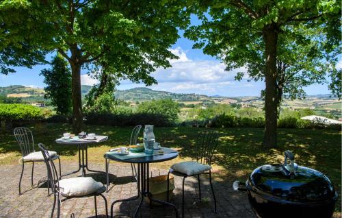 two tables and chairs with a view of a garden at 2 Bedroom Gorgeous Home In Cartoceto in Cartoceto