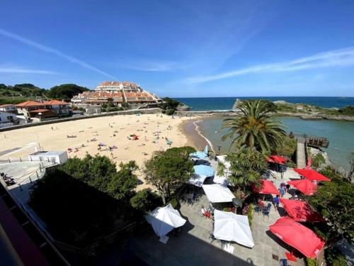 a beach with umbrellas and people on the sand at Hotel Alfar in Isla