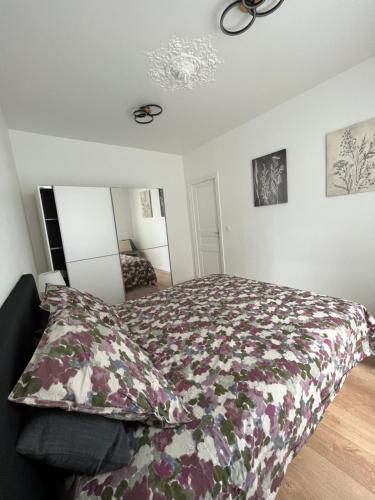 une chambre avec un lit avec une couette fleurie dans l'établissement Pretty Purple, à Clichy