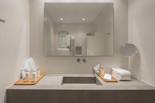 ein Bad mit einem Waschbecken und einem Spiegel in der Unterkunft NĒRO Suites by NOMÉE Hospitality Group in Imerovigli