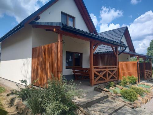 une maison avec un porche et une clôture dans l'établissement Bieszczadzki Krakowiak 575-894-584 lub 535-595-732, à Polańczyk