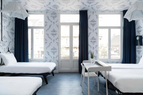 a room with two beds and a table and windows at Kaboom Maastricht in Maastricht