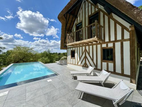 une maison avec une piscine et des chaises blanches dans l'établissement Villa Pier'Art, à Touques