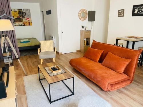un salon avec un canapé orange et une table dans l'établissement Bel Appartement Lumineux - 2 Voyageurs, au Mans
