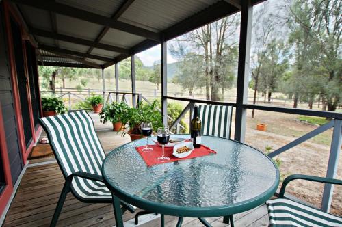a table with two chairs and wine glasses on a porch at Serenity Grove in Broke