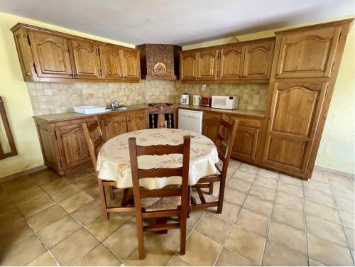 une cuisine avec des armoires en bois et une table et des chaises dans l'établissement Gîte de caractère, à Saint-Martial-de-Nabirat