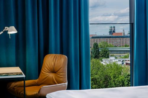 una silla frente a una ventana con una cortina azul en Motel One München - Deutsches Museum en Múnich