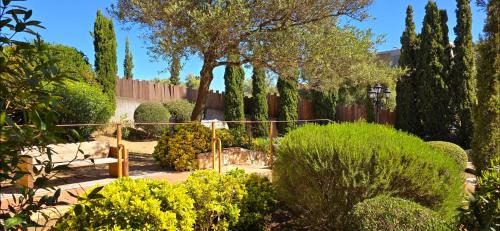 a garden with trees and bushes and a fence at Hotel Cala di l'Oru in LʼÎle-Rousse