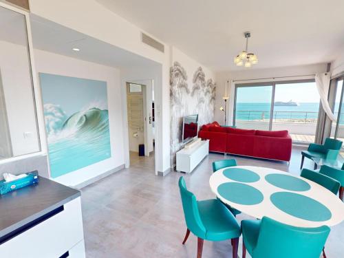 - un salon avec une table, des chaises et un canapé rouge dans l'établissement Magnifique 3P face mer avec terrasse de 46m² et parking privé - FR-1-196-250, à Menton