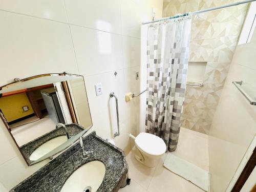 Un baño con lavabo, inodoro y espejo. en Pousada Acalanto, en Aracaju