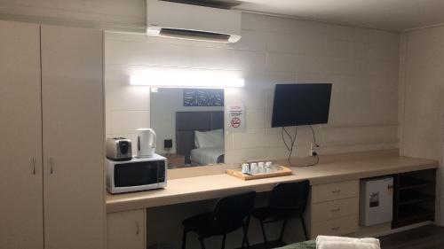 a room with a desk with a microwave and a mirror at Gladstone CBD Motel in Gladstone