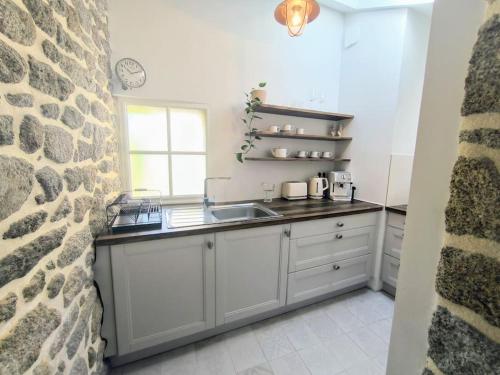 une cuisine avec un évier et un mur en pierre dans l'établissement Maisonette proche de la mer, à Loctudy