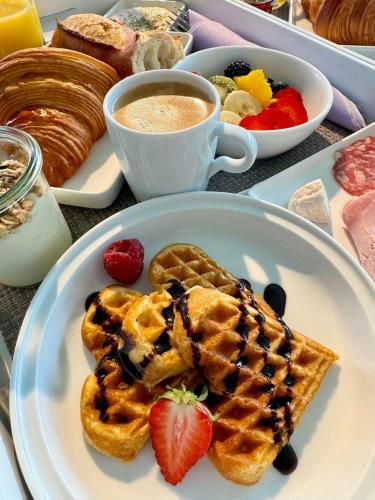 a plate of waffles with strawberries and a cup of coffee at Le Pavillon M, Piscine et Spa au pied du château, Petit-Déjeuner inclus, Parking privé in Grignan