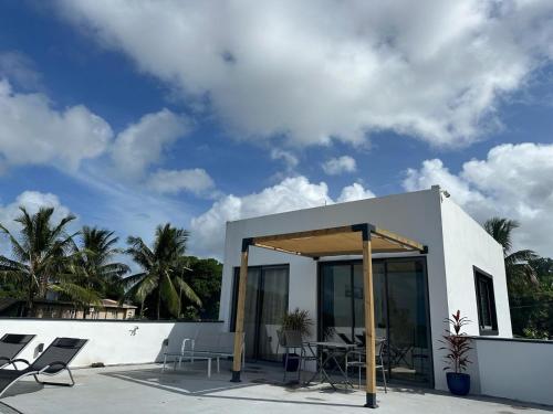a white house with chairs and a patio at Appartement moderne face à la mer in Mahébourg