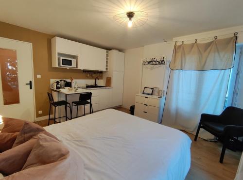 Cet appartement comprend une chambre avec un lit blanc et une cuisine. dans l'établissement Studio Vannes - centre-ville et parking, à Vannes