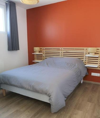Ce lit se trouve dans une chambre dotée d'un mur orange. dans l'établissement T2 proche Marais avec vue cathédrale et garage à moto, à Bourges