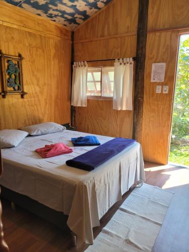 - une chambre avec un lit dans une pièce dotée d'une fenêtre dans l'établissement Piratas Cabanas Camping Bar, à Parati