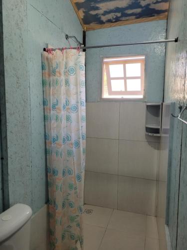 łazienka z zasłoną prysznicową i oknem w obiekcie Piratas Cabanas Camping Bar w mieście Paraty