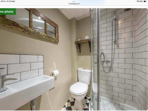 a bathroom with a toilet and a glass shower at The Old Candle Shop in Little Walsingham