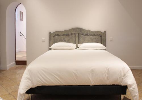 une chambre avec un grand lit avec des draps et des oreillers blancs dans l'établissement Bastide Des Oliviers, aux Arcs-sur-Argens
