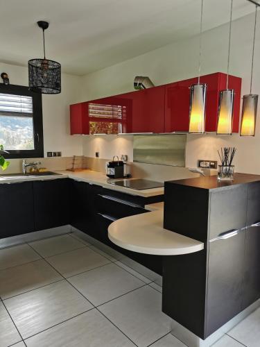 - une cuisine avec des placards rouges et une table dans l'établissement Le Rooftop du 10, à Annecy